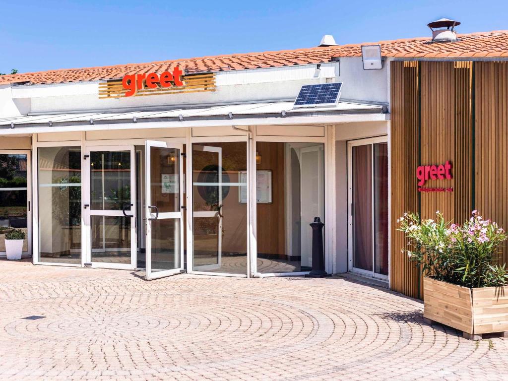 een gebouw met glazen deuren en een bord erop bij Greet Hôtel Castres Saix in Saix