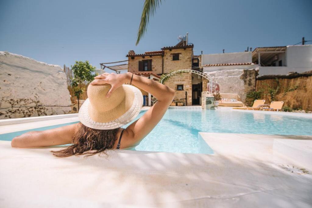 a woman in a hat sitting next to a swimming pool at Villa Hidden Gem Crete in Pangalochori