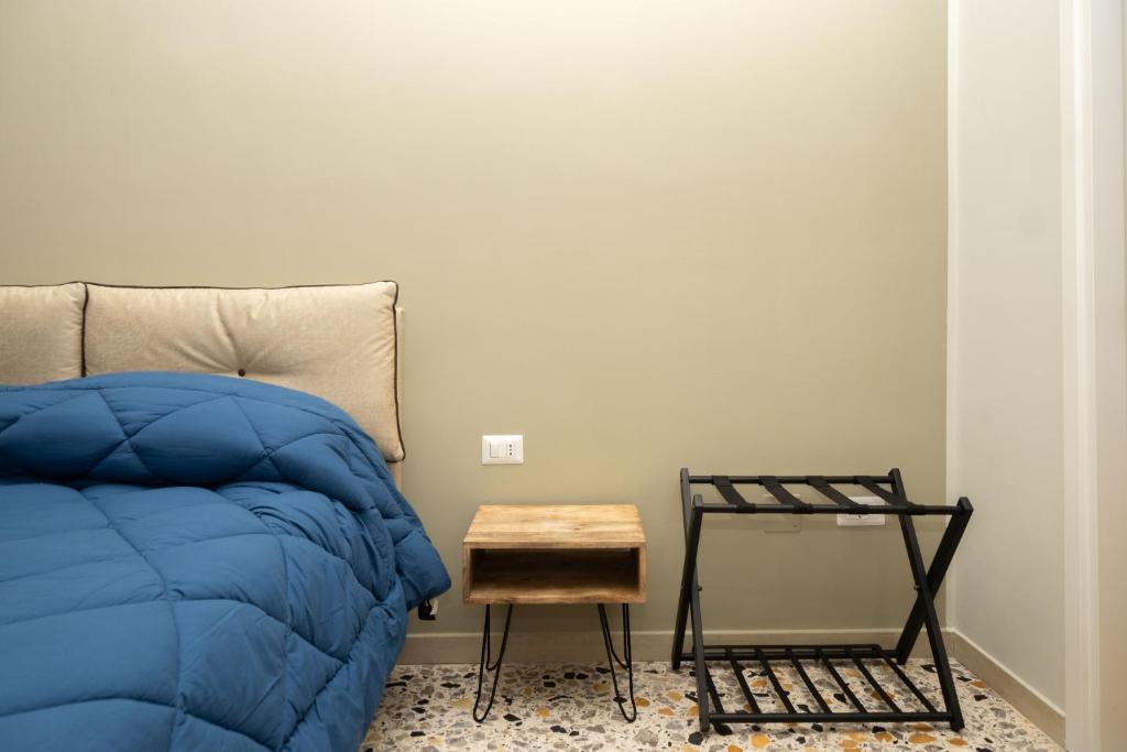 Un dormitorio con una cama azul y una mesa en Pignuol Rooms - nel cuore di Marigliano, en Marigliano