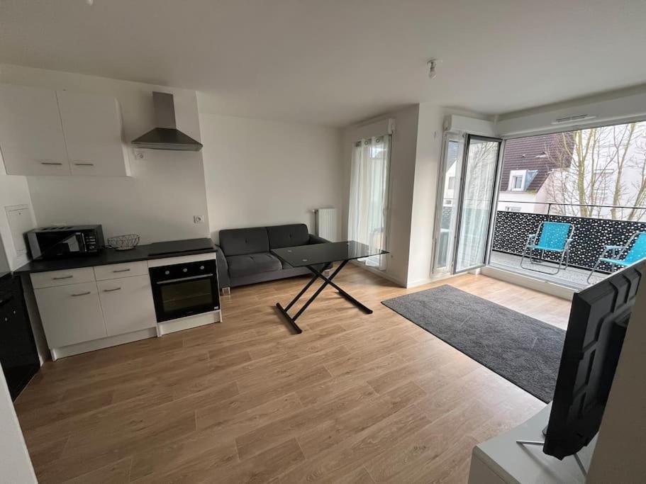 eine Küche und ein Wohnzimmer mit einem Sofa und einem Tisch in der Unterkunft Appartement T2 2e etage parking gratuit sur place in Cergy