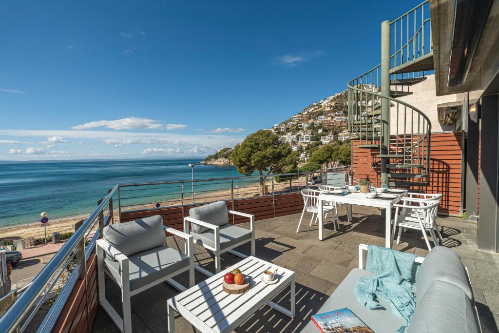 a balcony with a table and chairs and the ocean at Apartamento ático primera línea Playa Canyelles in Roses