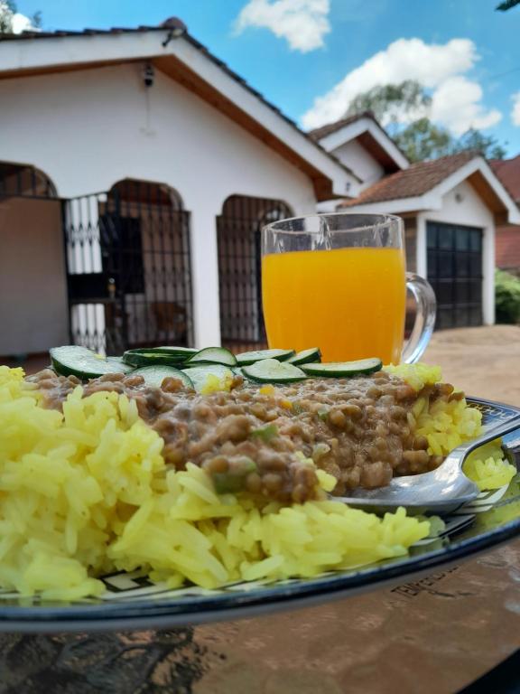 a plate of food with beans and vegetables and a glass of orange juice at Indovu Back Packers in Nairobi
