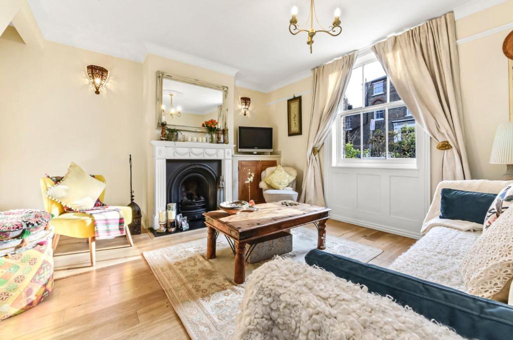 a living room with a couch and a fireplace at Victorian cottage in Brixton! in London