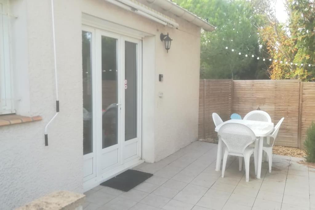 een patio met een witte tafel en stoelen erop bij Gîte aux Aspres Logement de 65m² (4pers) in Fontcouverte