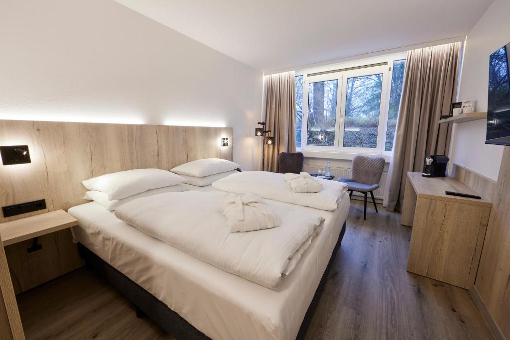 sypialnia z dużym łóżkiem z białą pościelą w obiekcie Hotel Bredeney w Essen