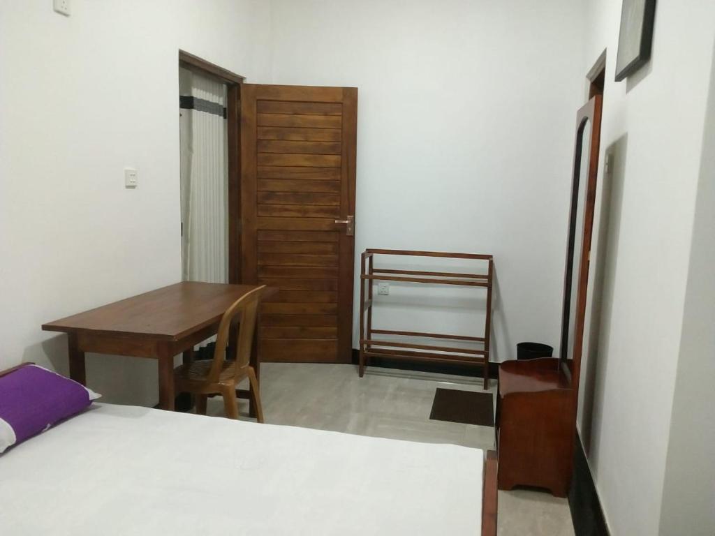 een slaapkamer met een bed, een bureau en een tafel bij Sahasna Guest House in Diyatalawa
