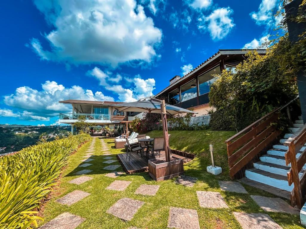 une maison sur une colline avec terrasse et pelouse dans l'établissement Chris Park Hotel, à Campos do Jordão