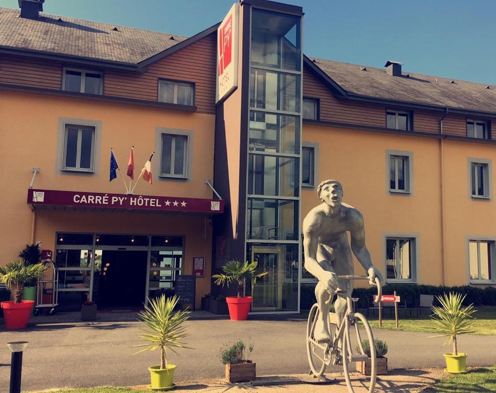 Eine Statue eines Mannes, der vor einem Gebäude Fahrrad fährt. in der Unterkunft Carré Py' Hôtel in Bagnères-de-Bigorre