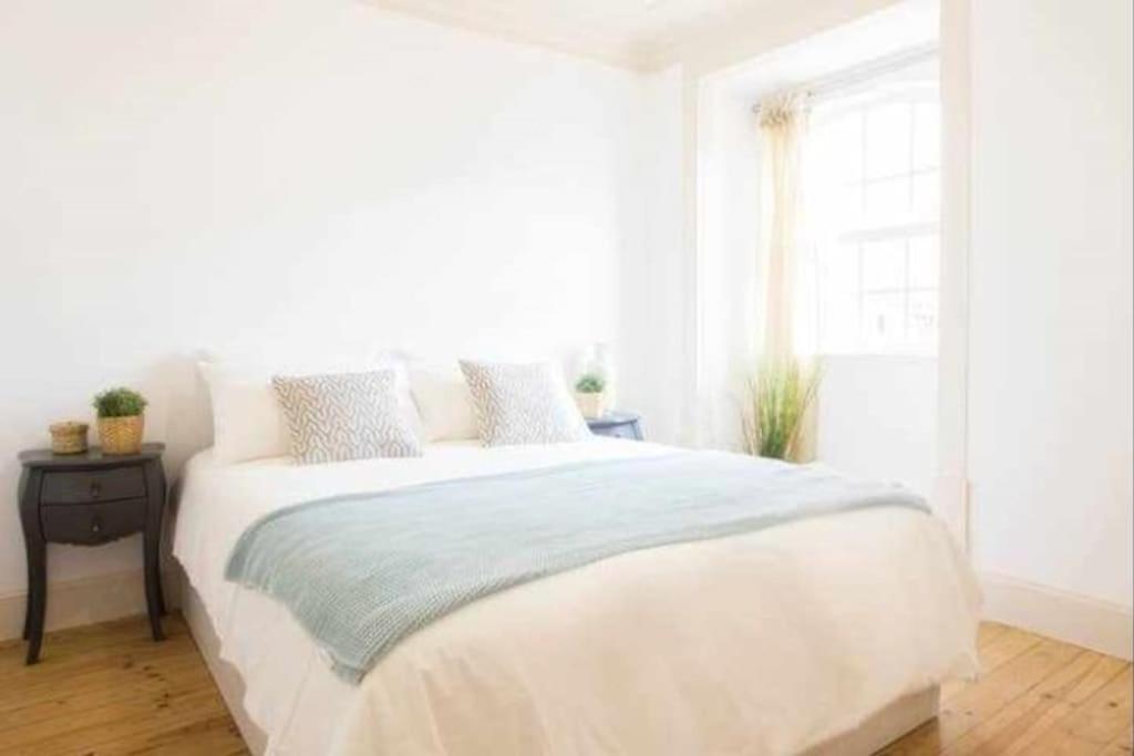 um quarto branco com uma cama grande e uma janela em Moeda '60 - Downtown Apartment em Coimbra