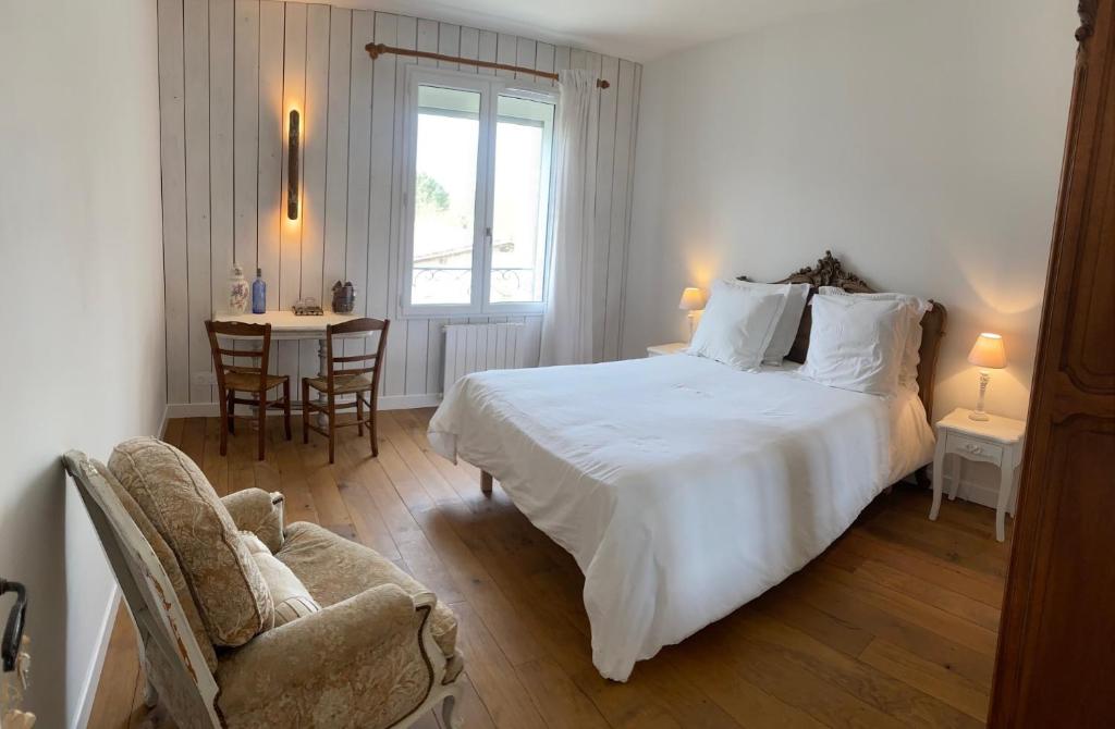 a bedroom with a white bed and a chair and a table at Maison d hôtes Les Chantours dans réserve naturelle 15 hectares in Saint-Antoine-Cumond