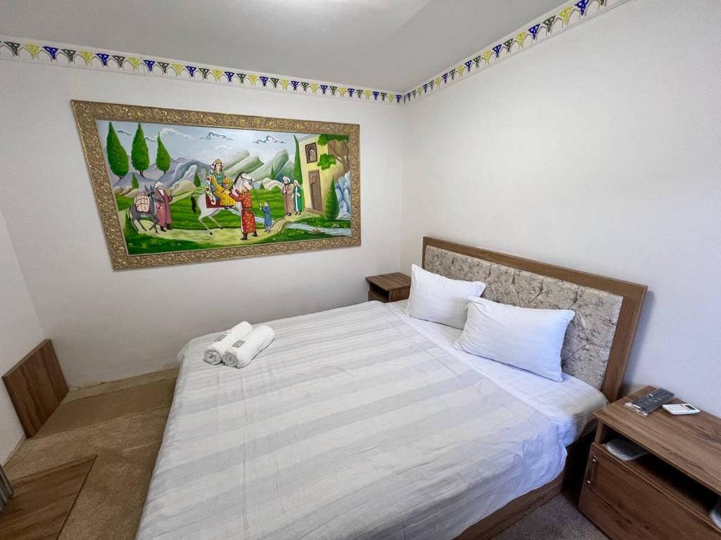 a bedroom with a large bed with a painting on the wall at Hotel Afsona old city in Bukhara