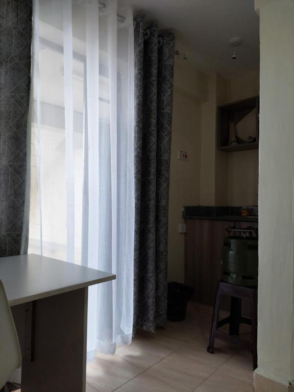Zimmer mit einem Fenster mit Vorhängen und einem Tisch in der Unterkunft Kim's BNBs in Meru