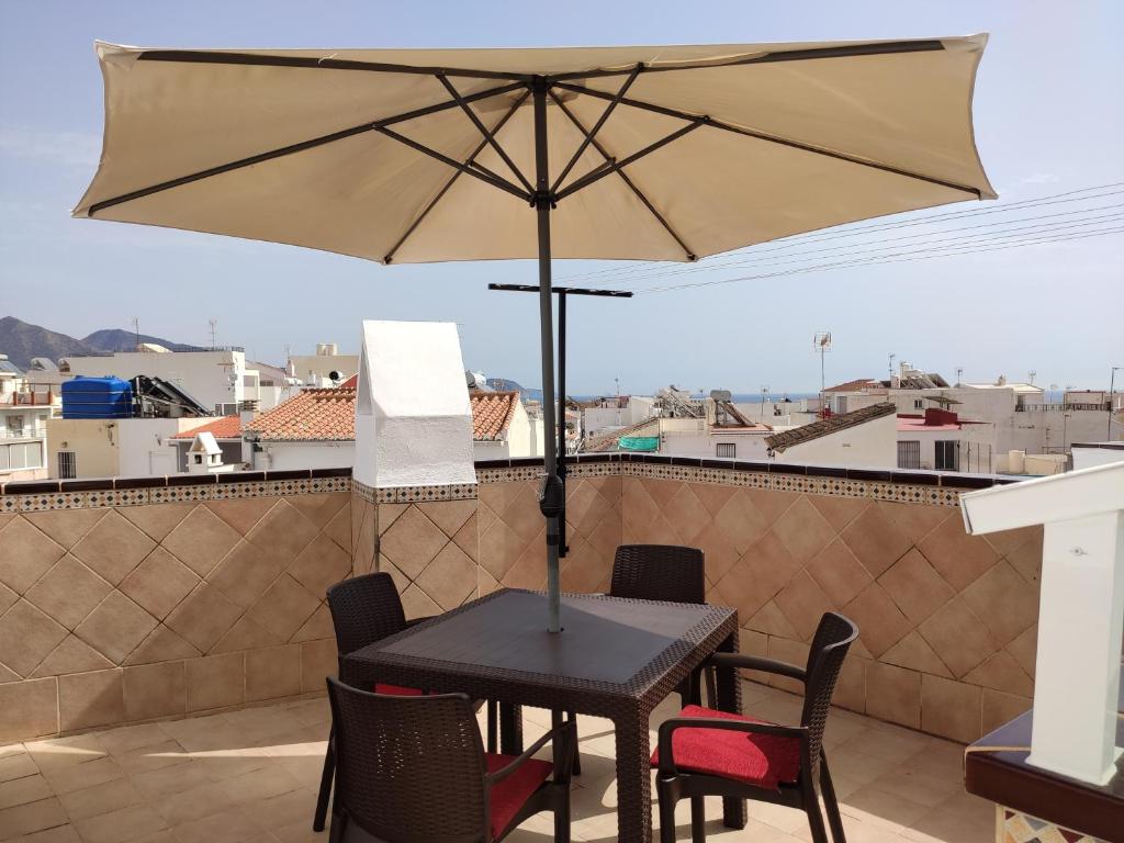 una mesa y sillas con una sombrilla en el balcón en Hostal Ana - Adults Recommended, en Nerja