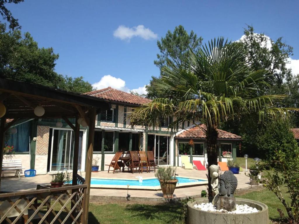 une maison avec un palmier et une piscine dans l'établissement Espace, calme, confort, à Saint-Michel-Escalus