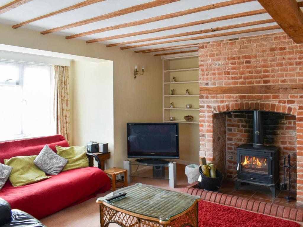 a living room with a brick fireplace and a red couch at Findley Cottage 