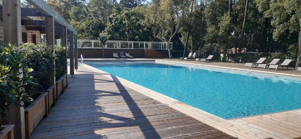 a swimming pool with chairs and a wooden deck at Chalet la lande in Ondres