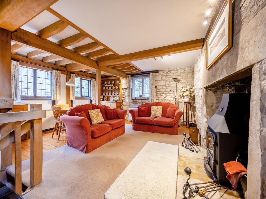 a living room with red chairs and a stone fireplace at Capp Mill in Painswick