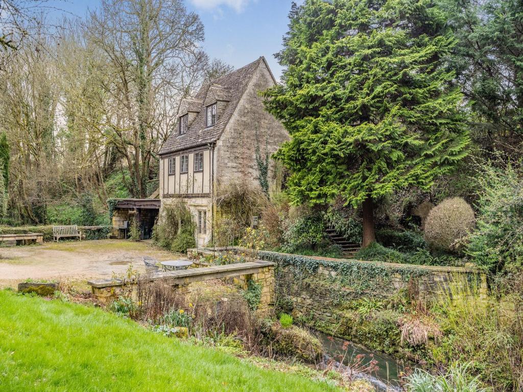 une ancienne maison en pierre avec un jardin et un étang dans l'établissement Capp Mill, à Painswick