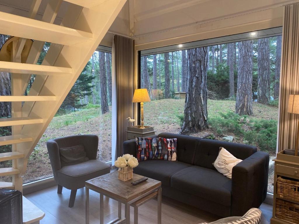 uma sala de estar com um sofá e cadeiras e uma grande janela em La Forestière - Face au 10 em Neufchâtel-Hardelot