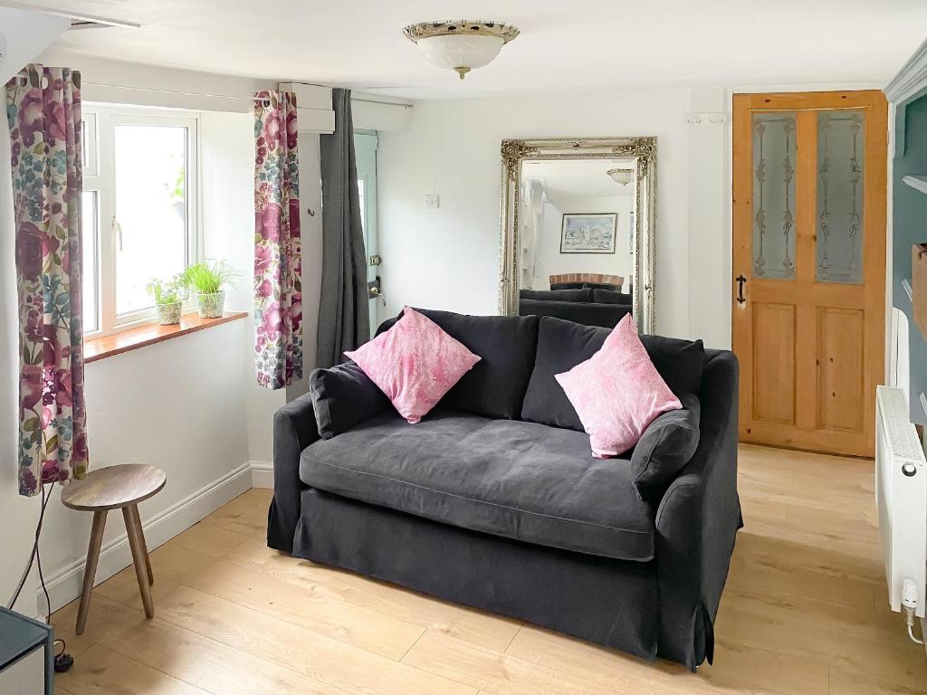 a living room with a black couch with pink pillows at Smithy End in Chard
