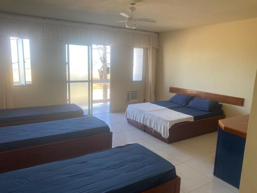 a bedroom with two beds and a large window at Maria Flor Pousada e kitnet in São Mateus