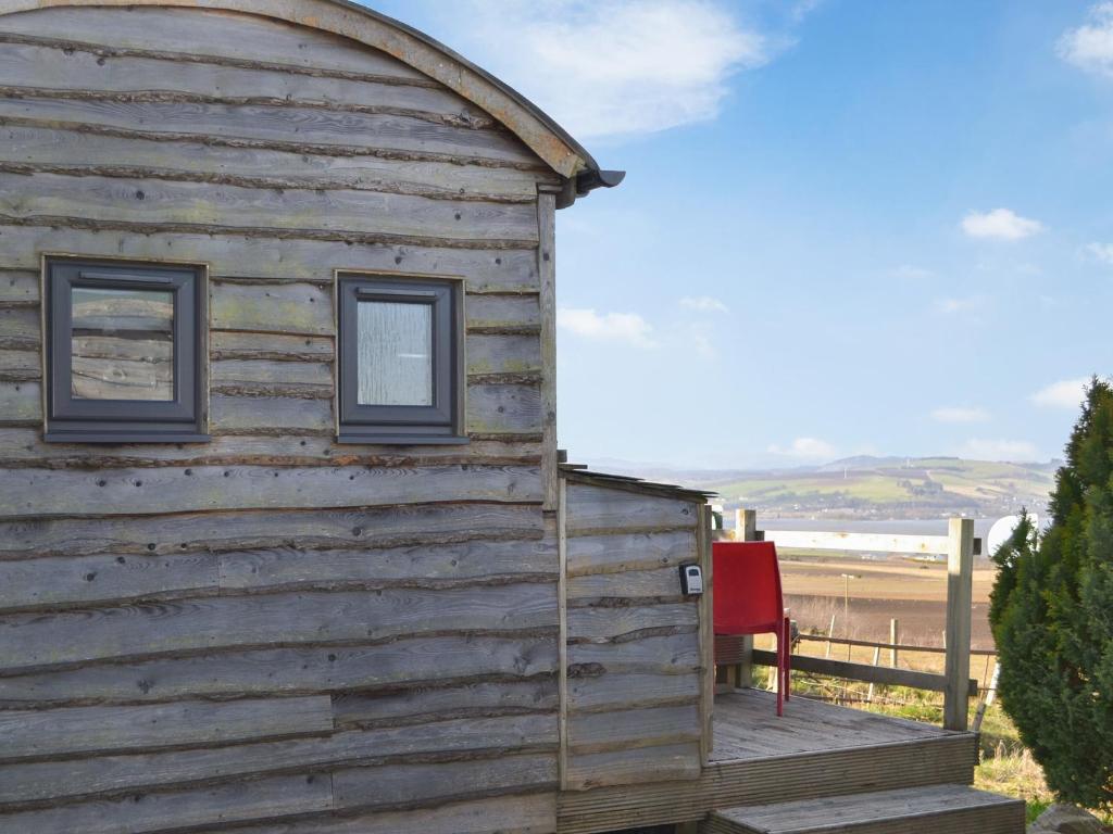 a wooden building with two windows on a deck at The Shepherds Hut - Uk46633 in Culbokie