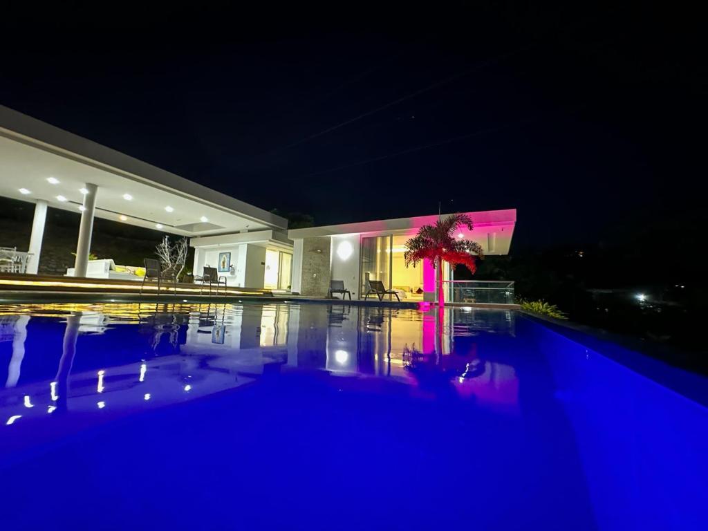 een huis met een zwembad in de nacht bij LINDA FINCA PALMAS DE BETANIA in Villeta