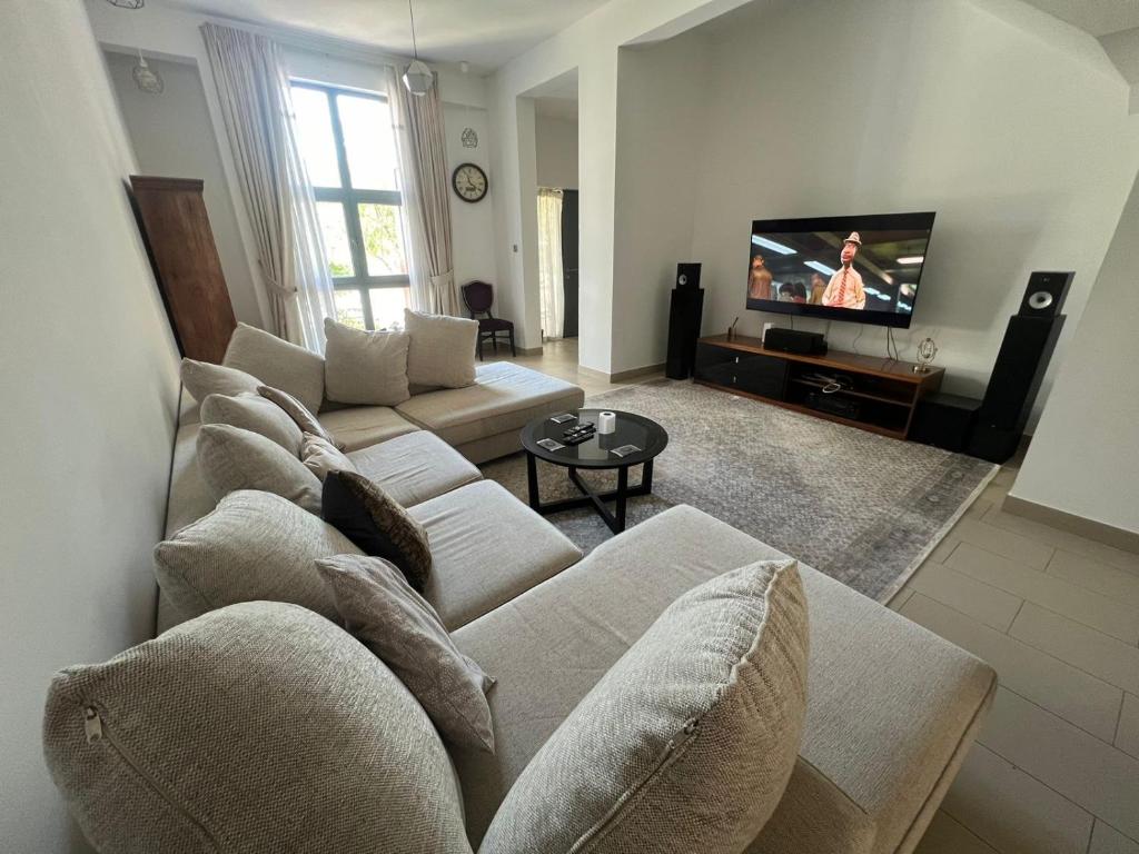 sala de estar con sofá y TV en Townhouse Private Room, en Dubái