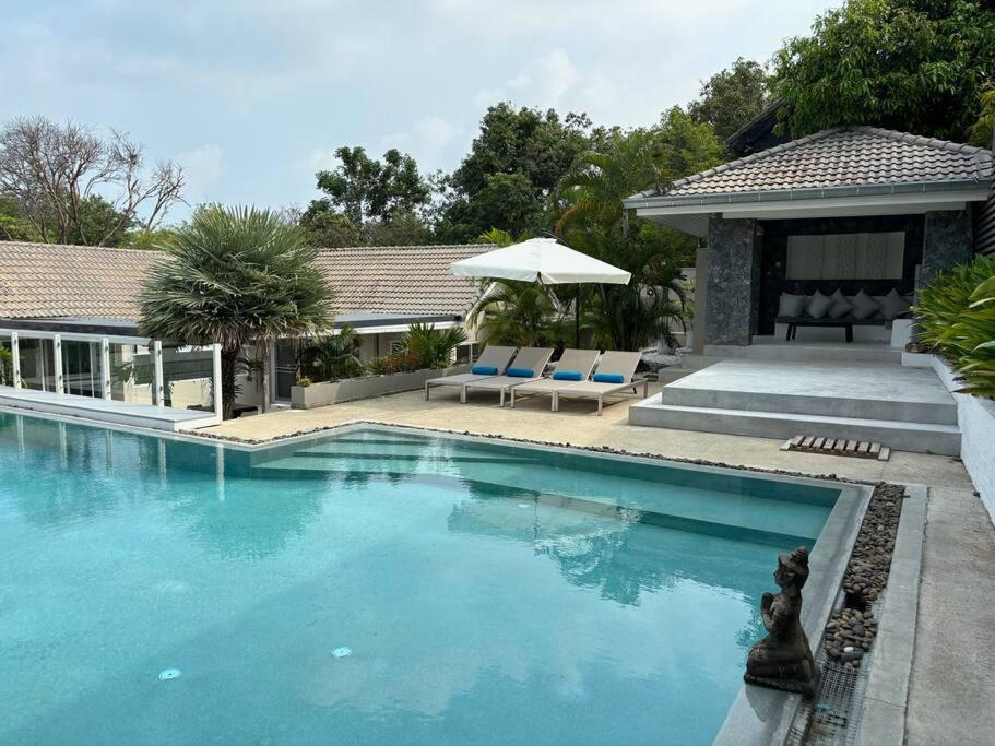 una piscina con due sedie e un ombrellone di UMiiMAAN pool villa, 4BR, 4BA a Ko Samui