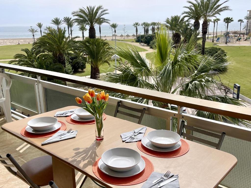 a table with plates and flowers on a balcony with the beach at APARTBEACH ARRECIFE y FRENTE PLAYA in La Pineda