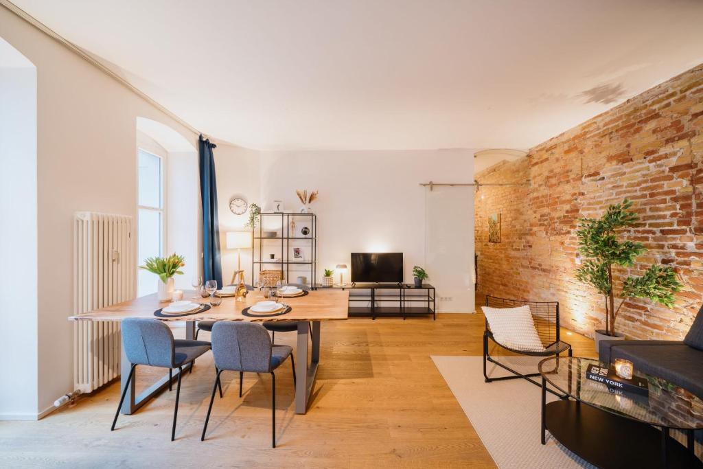 - un salon avec une table et des chaises ainsi qu'un mur en briques dans l'établissement Urban Retreat - City Center Apartment in central Berlin BY HOMELY, à Berlin