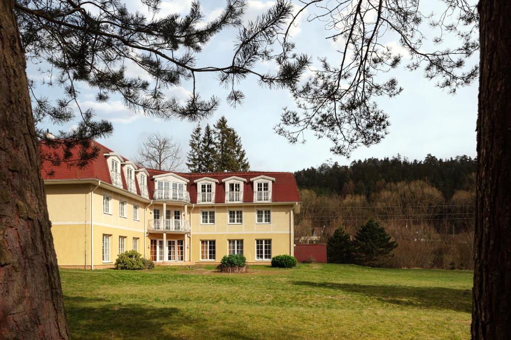 una gran casa amarilla con techo rojo en Hotel Adršpach en Adršpach