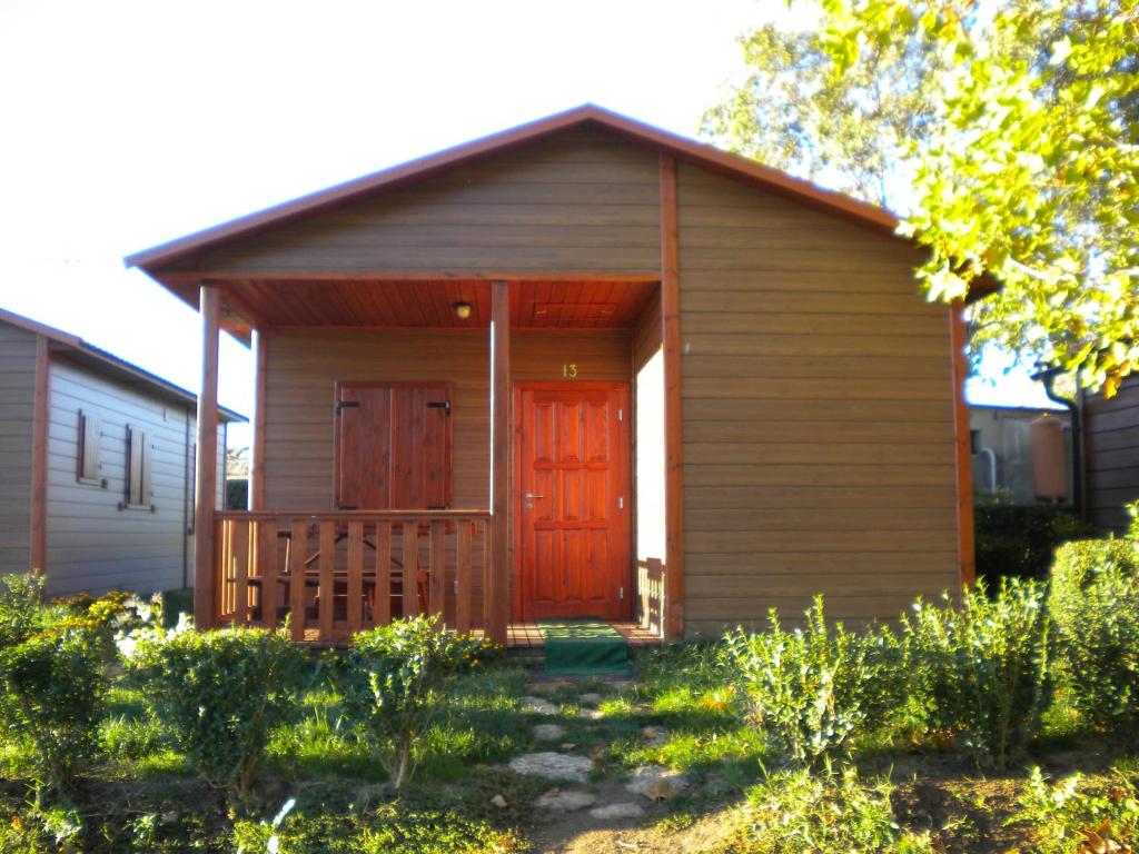 a small wooden building with a red door at CAMPING-BUNGALOWS-CABAÑAS LA VERA in Jarandilla de la Vera