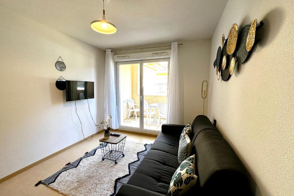 a living room with a black couch and a television at E20 Les Naïades- 2 bedrooms for 5 people ! in Avène