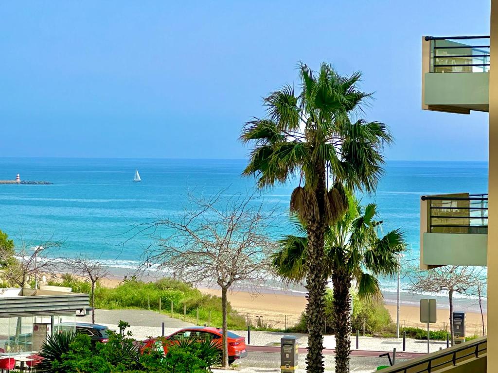 vistas a una playa con palmeras y al océano en Lovely beachfront apartment with Aircon/WIFI, en Portimão