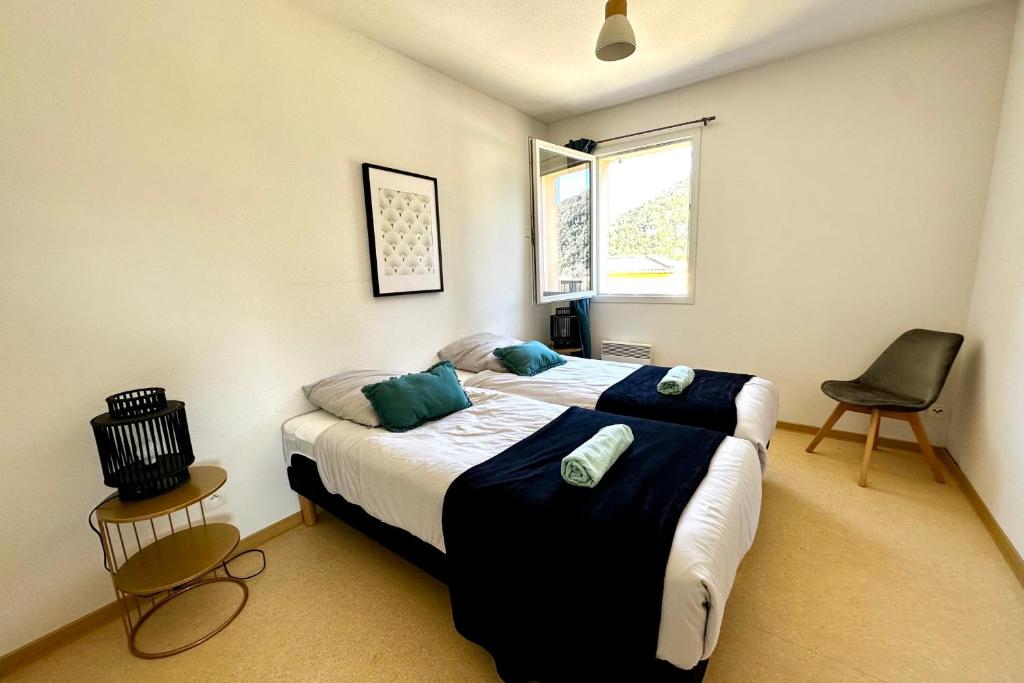 une chambre avec deux lits et une chaise et une fenêtre dans l'établissement Les Naïades E21 - 2 bedrooms for 5 people !, à Avène