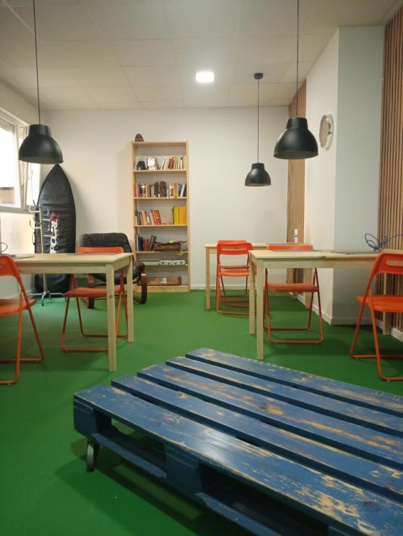 a room with tables and chairs and a bench at Hostel Allegro in Santander