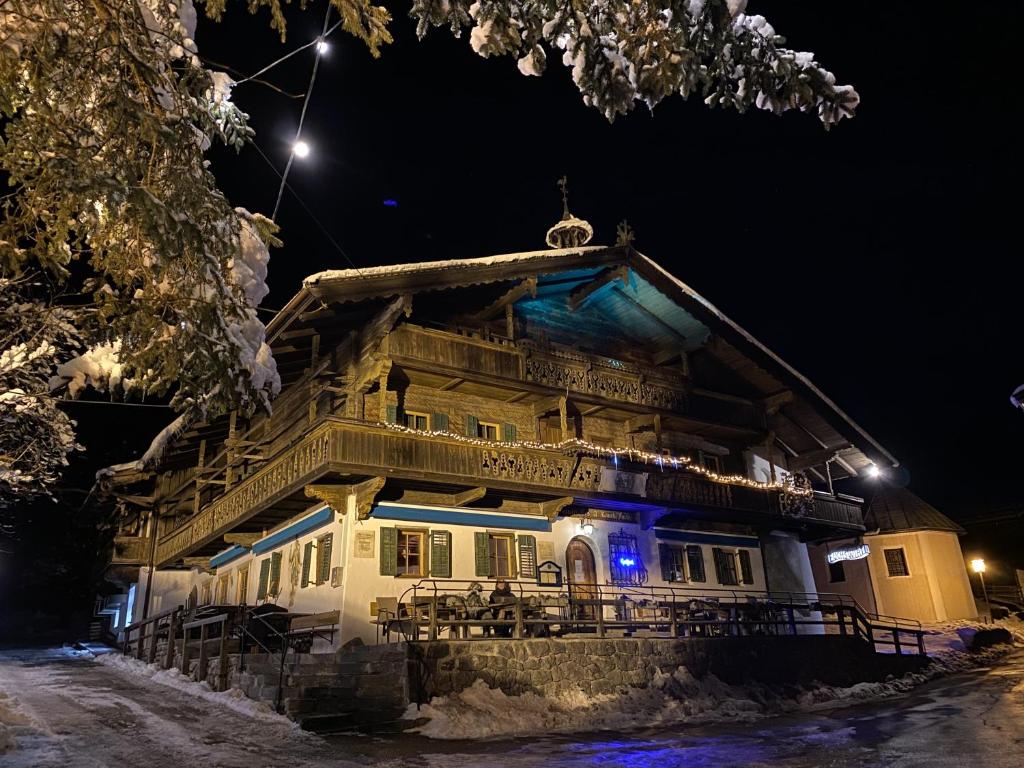 un viejo edificio con luces azules en él por la noche en Fuchswirt Kelchsau Landgasthof-Hotel, en Hopfgarten im Brixental