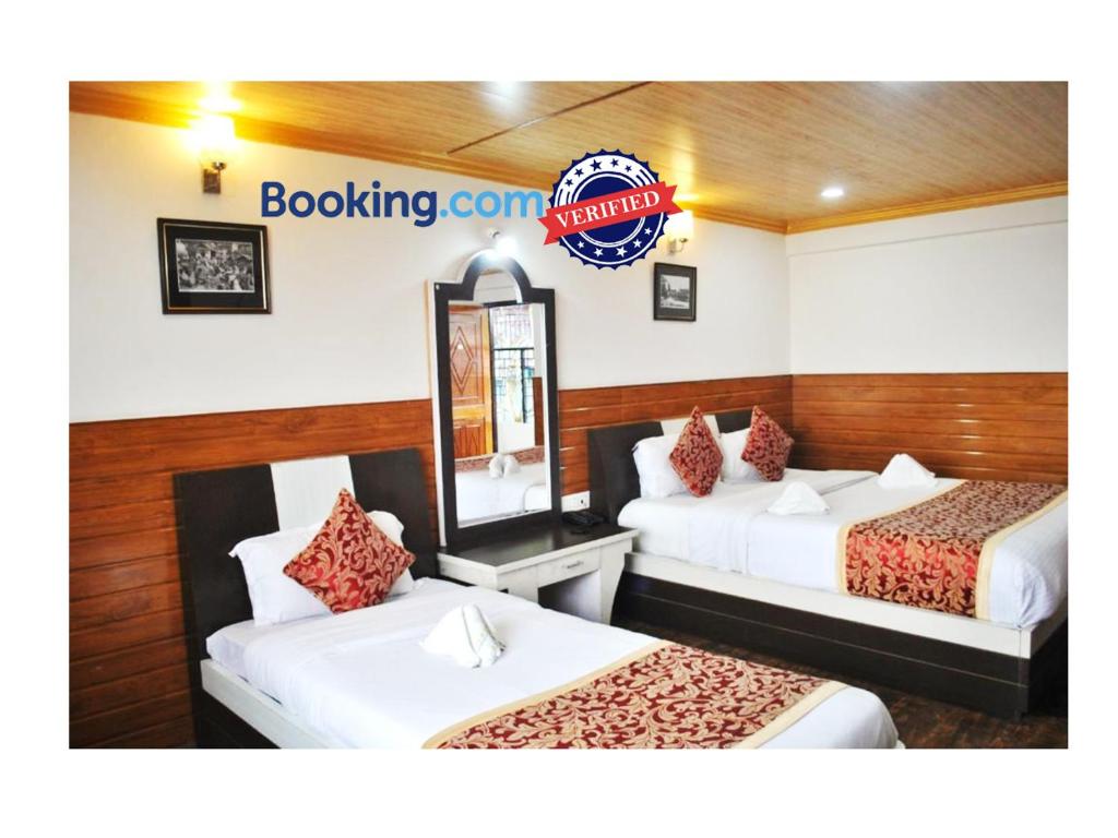 a hotel room with two beds and a mirror at Goroomgo Kasturi Palace Darjeeling - Luxury Room with Parking Facilities - Best Seller in Darjeeling