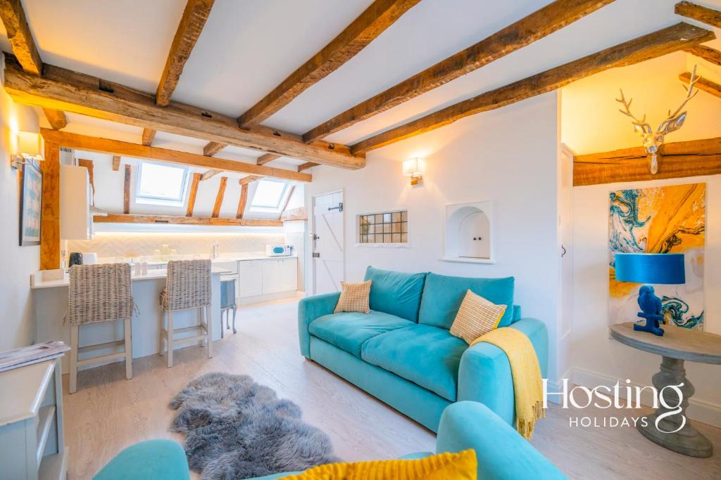 een woonkamer met een blauwe bank en een keuken bij Stable Annex Bisham - Vibrant 1 Bed With Parking in Marlow