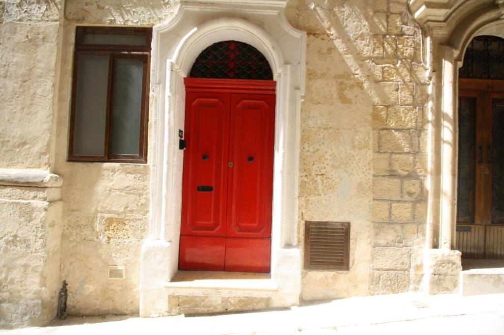 una puerta roja en el lateral de un edificio en Old refurbished Apartment in Bormla, en Cospicua