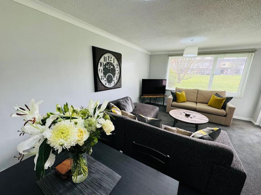 a living room with a couch and a vase of flowers at Modern & secluded home in Frenchay in Bristol