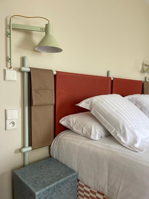 a bed with a red head board and a lamp at Hotel des Victoires - Restaurant in Cannes