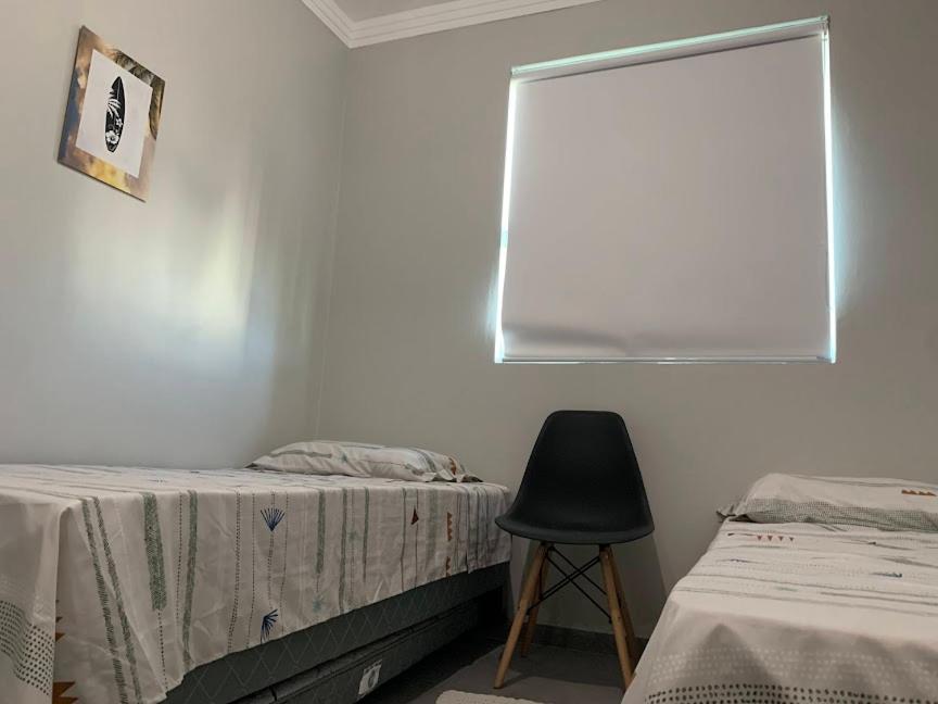 1 dormitorio con 2 camas, silla y ventana en BnB Praia Mole e Barra da lagoa -piscina-churrasco, en Florianópolis