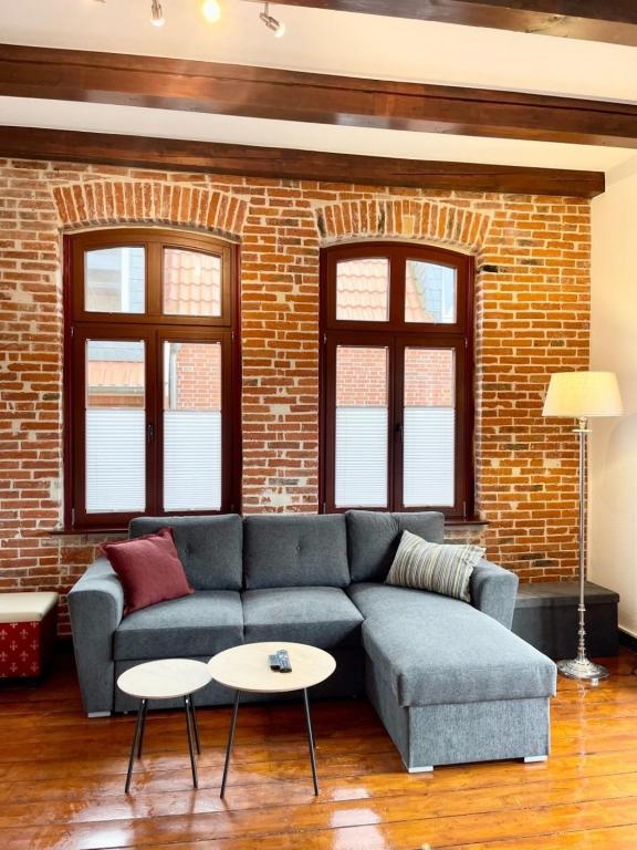 a living room with a blue couch and a brick wall at Charmante Ferienwohnung Greta 109 in der City von Norden in Norden