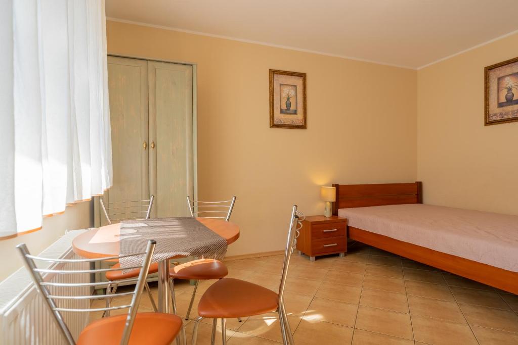 1 dormitorio con 1 cama, mesa y sillas en Słoneczna Przystań (pokoje z łazienkami), en Dźwirzyno