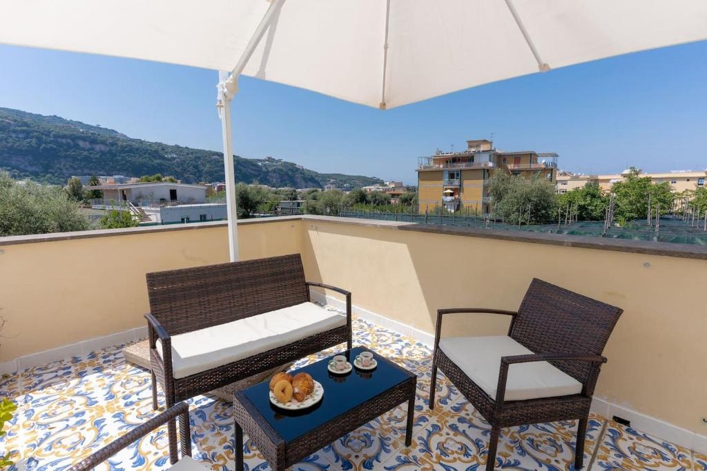 - un balcon avec 2 chaises, une table et un parasol dans l'établissement Sorrento Realty Holidays Pinnidys House, à Sorrente