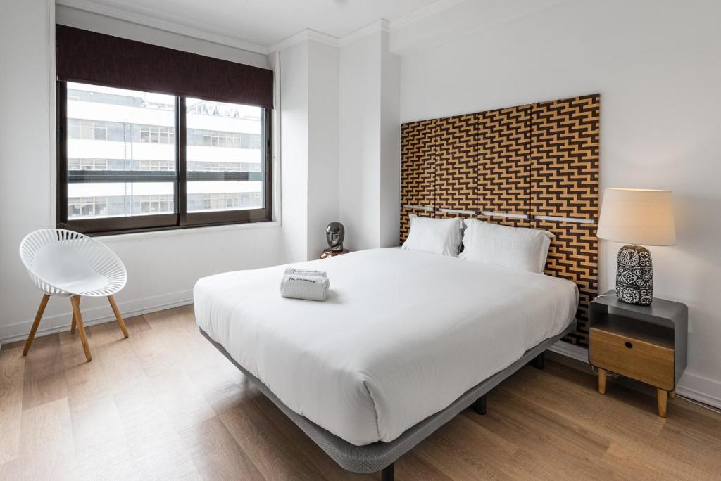 Un dormitorio con una gran cama blanca y una pared de ladrillo en GuestReady - Mystic Subdual, en Oporto