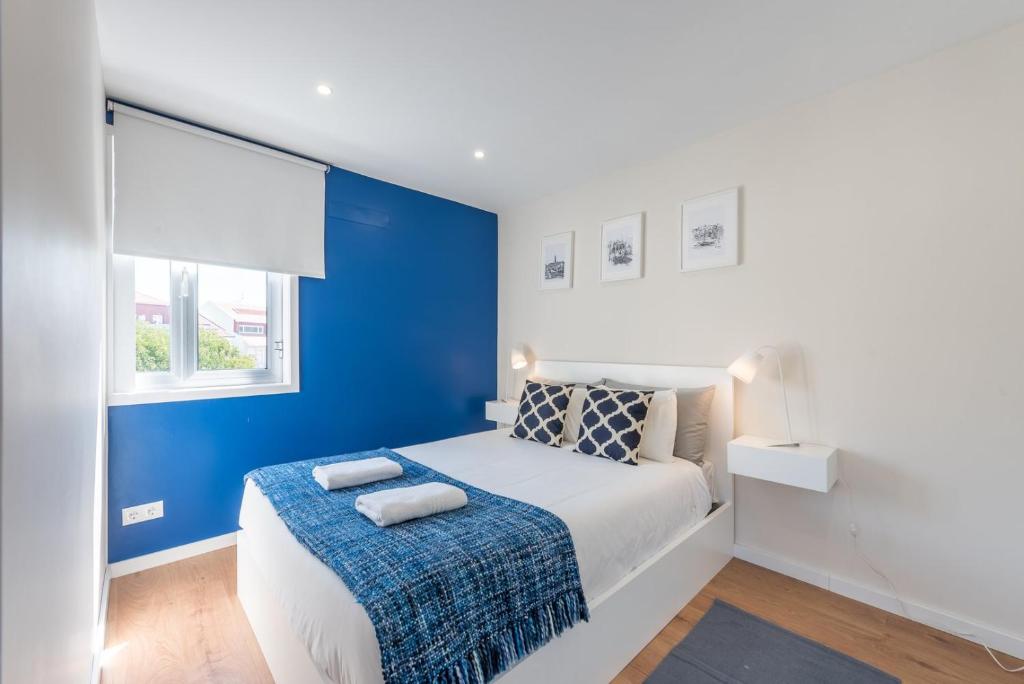 Dormitorio azul y blanco con cama y ventana en GuestReady - Theater Apartment en Oporto