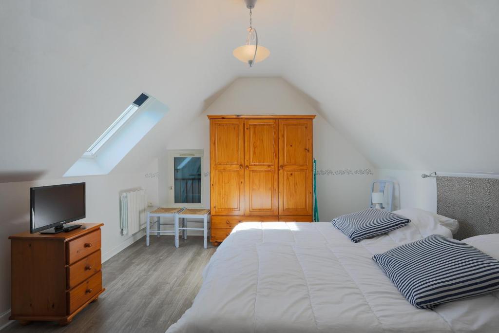 - une chambre avec deux lits et une commode avec une télévision dans l'établissement Charmante Maison en pierre rénovée, à Lanmodez